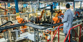 Person with clipboard monitoring a factory with robots